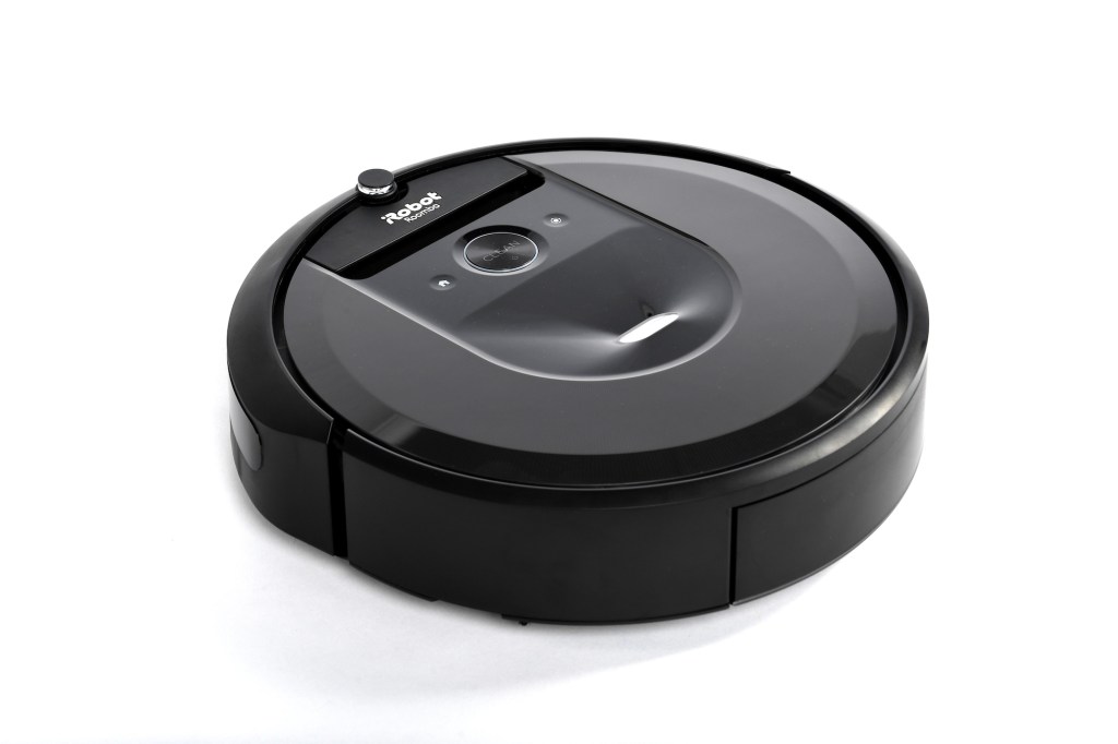 A black iRobot Roomba robot vacuum cleaner on a white surface