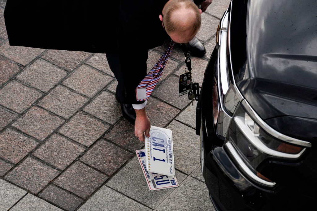 Officials transfer license plates of the motorcade ahead of the inauguration of President Joe Biden.