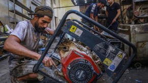 A worker repairs a portable generator in a workshop