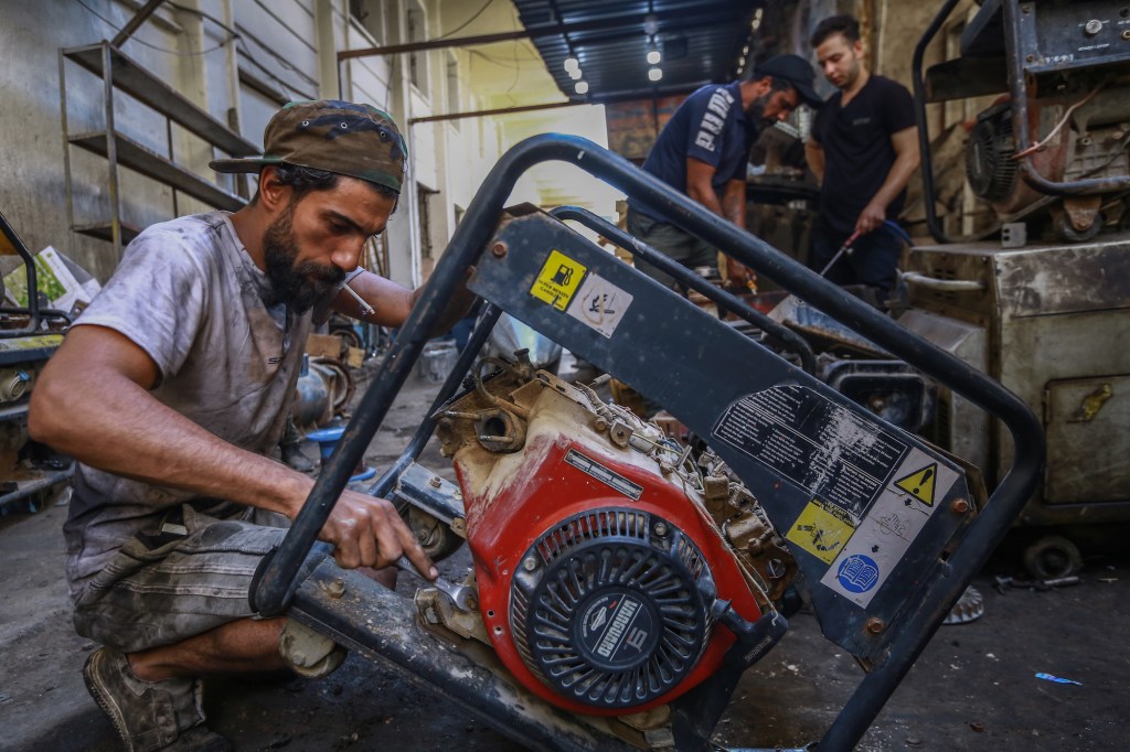 A worker repairs a portable generator in a workshop