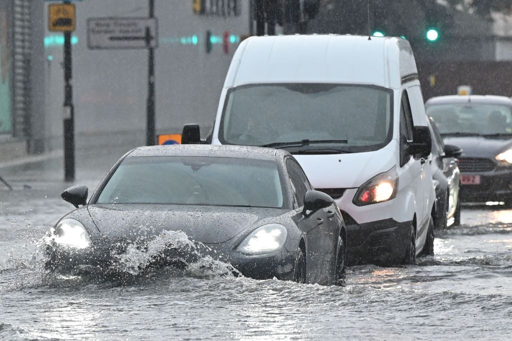 Cars drive through deep water on a flooded road