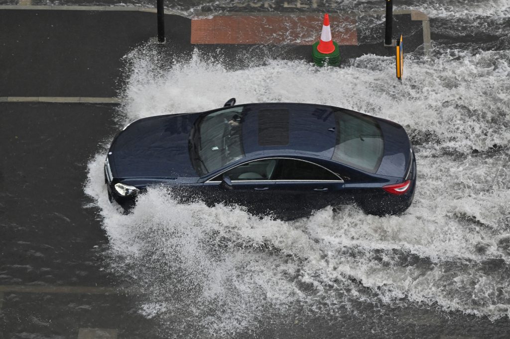 A car drives through deep water on a flooded road