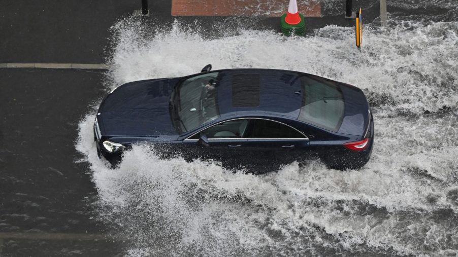 A car drives through deep water on a flooded road