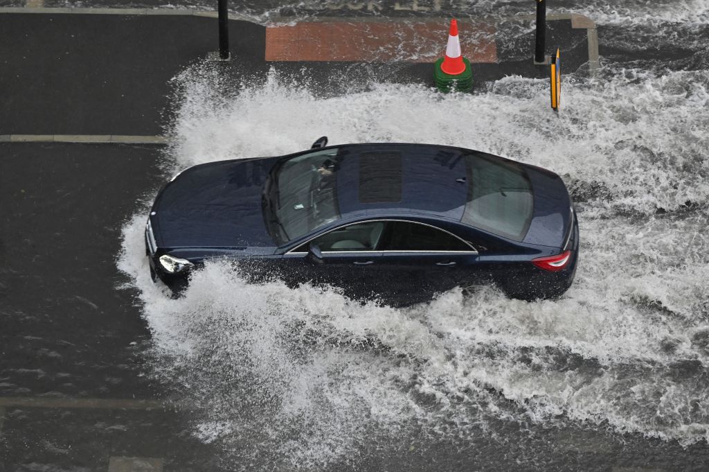 Cars drive through deep water on a flooded road