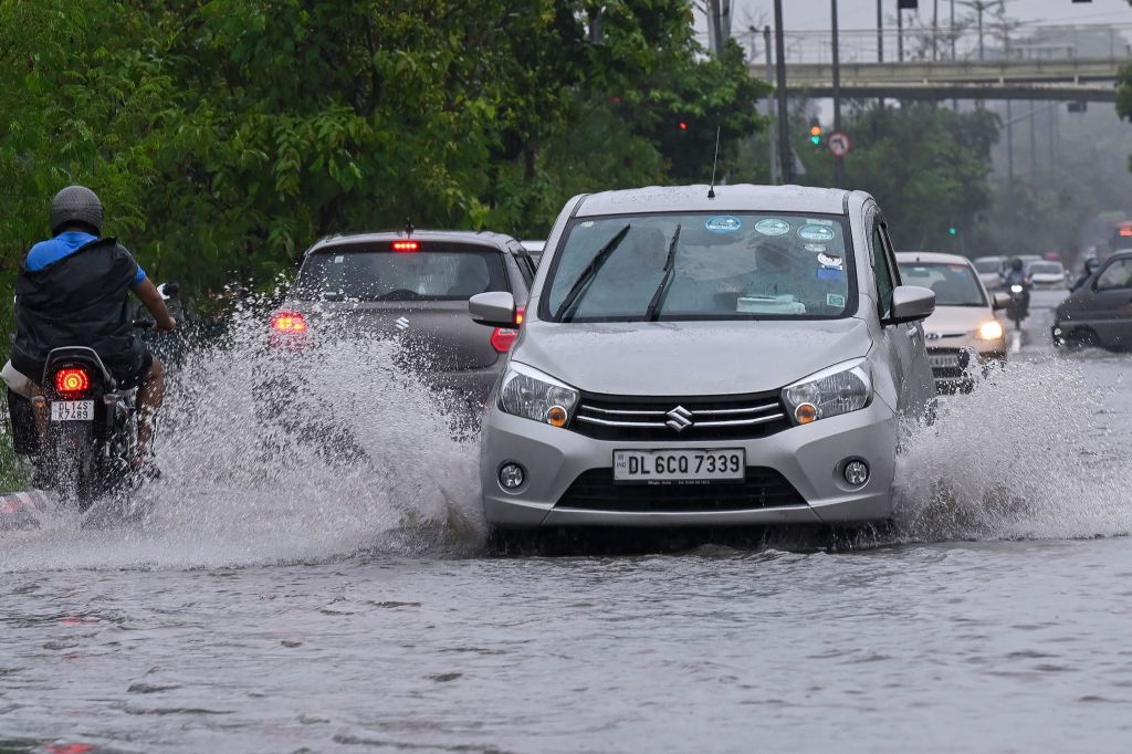 Vehicles drive along a water-logged road during heavy monsoon rains