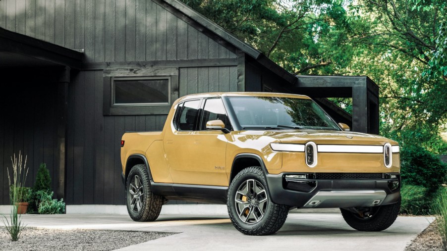 A yellow 2022 Rivian R1T parked in front of a home.