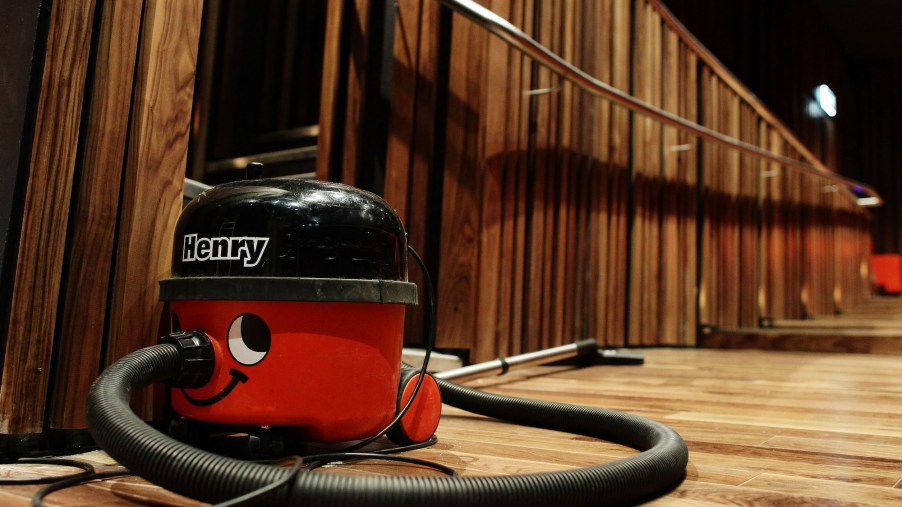 A shop vac sits on a wood floor in a wood-paneled auditorium