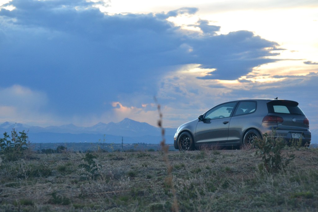 A gray Volkswagen GTI at sunset photographed with the Rocky Mountains in the background