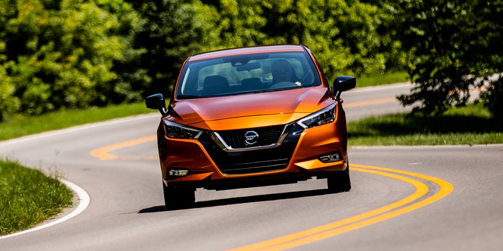 an orange 2021 Nissan Versa driving on a scenic winding road 