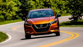 an orange 2021 Nissan Versa driving on a scenic winding road