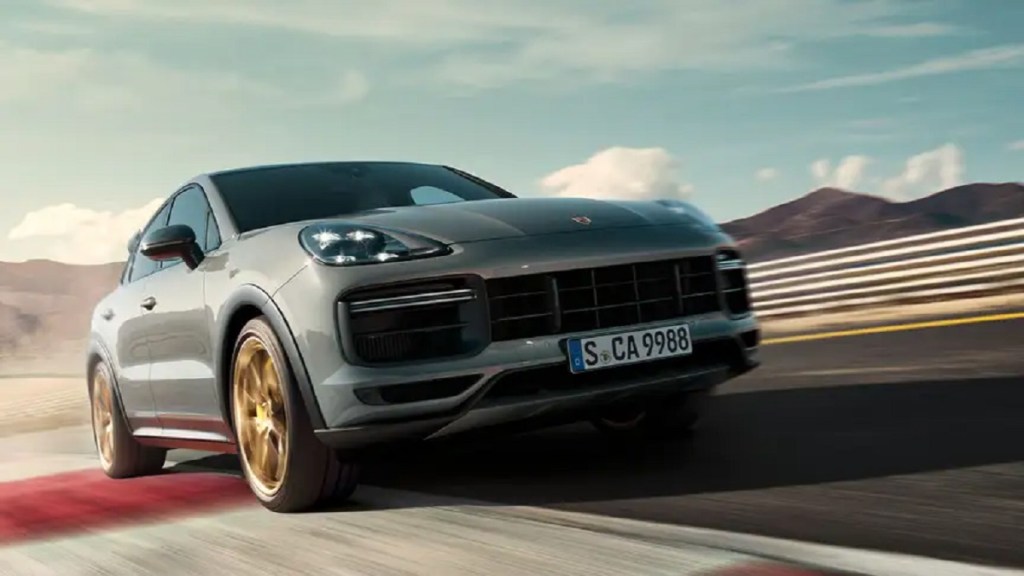 A gray 2021 Porsche Cayenne driving with mountains in the background.