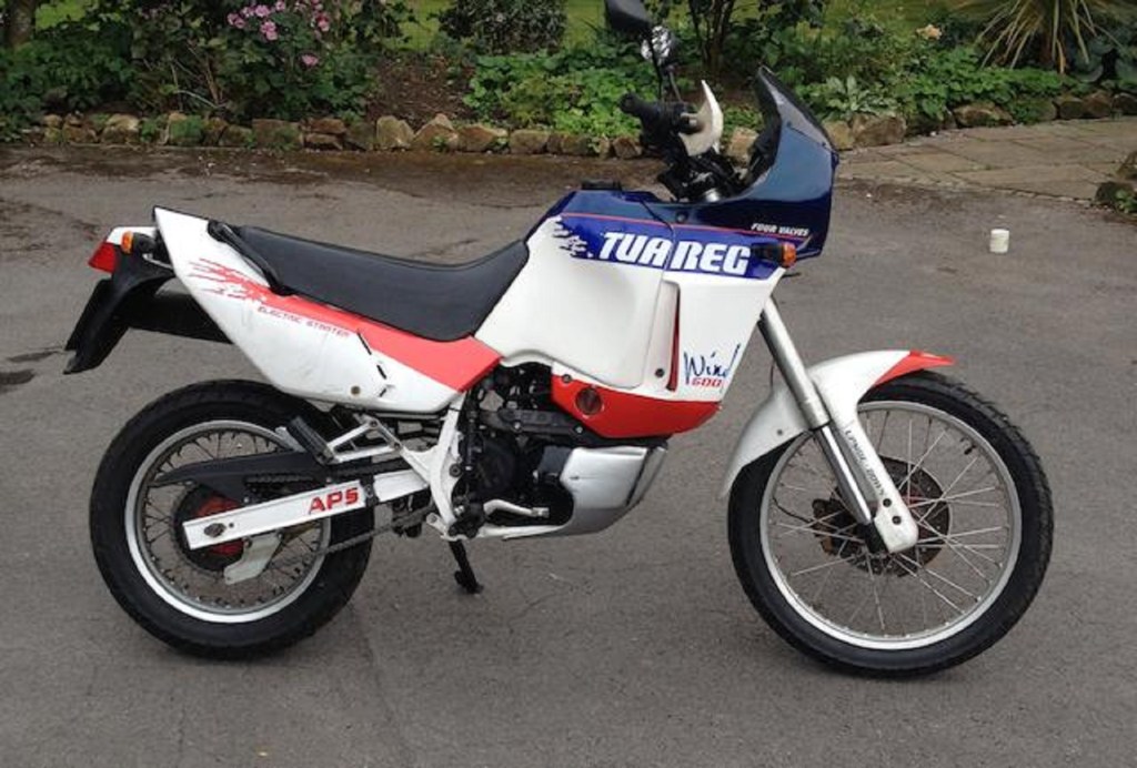 The side view of a white-red-and-blue 1989 Aprilia Tuareg Wind 600 in a parking lot