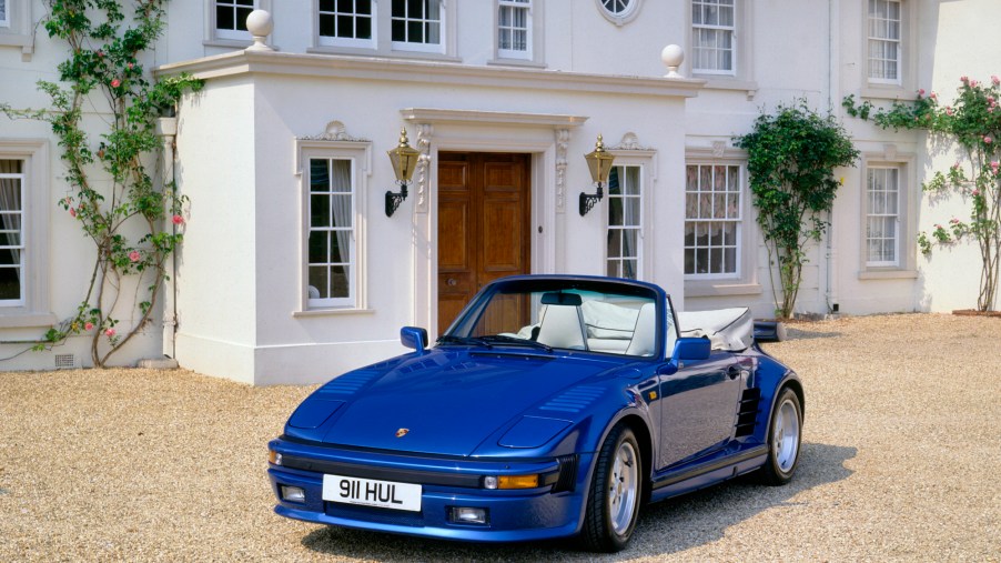A royal-blue 1989 Porsche 911 Turbo SE Cabriolet parked in front of an ornate white building