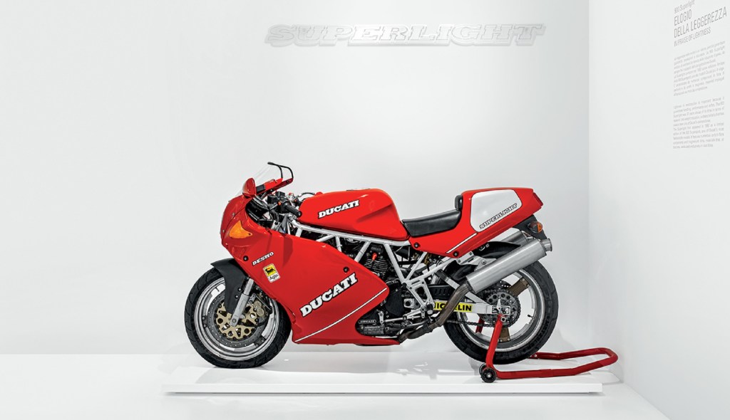 The side view of a classic red 1992 Ducati 900 SuperSport Superlight on a rear-wheel stand in the Ducati museum
