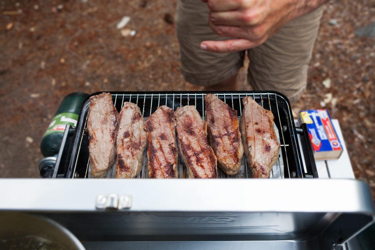 steaks grilling on a camping stove