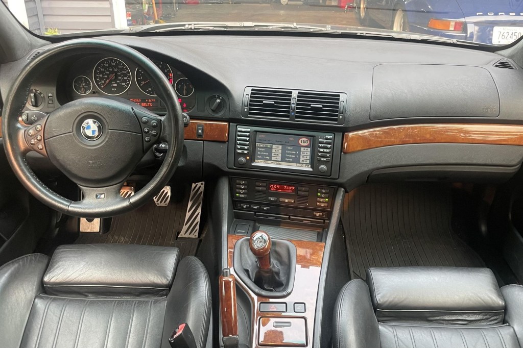 The black-leather-upholstered and wood-trimmed front seats and dashboard of a 2000 BMW E39 M5