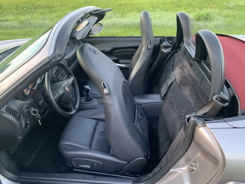 The side view of a tan-silver 2002 Porsche Boxster S's partial-black-leather interior