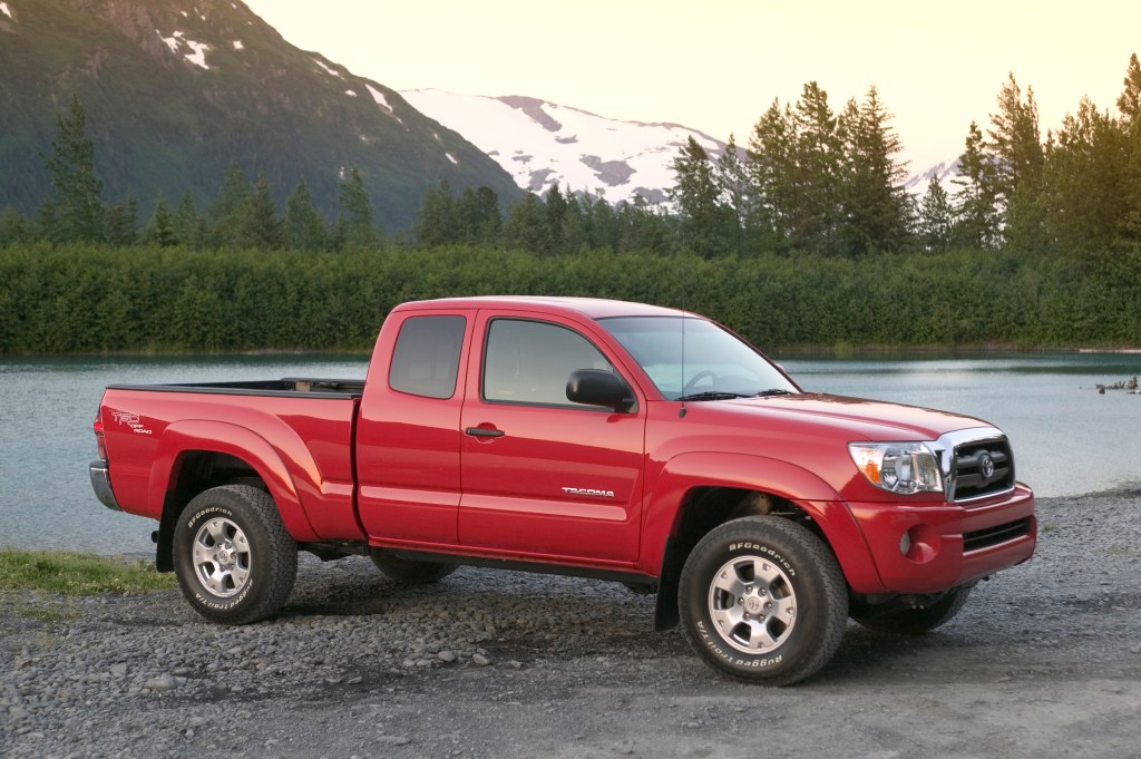 access cab used Toyota Tacoma from 2007 in a bright red color parked off-road near a lake with mountains
