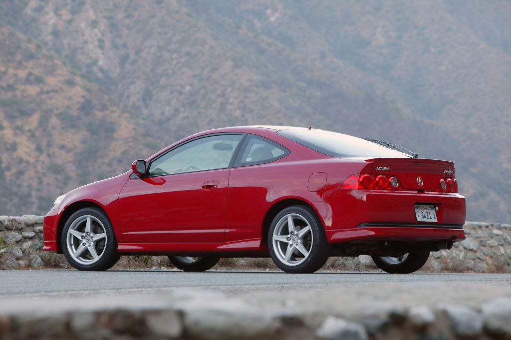 The rear 3/4 view of a red 2006 Acura RSX Type S on a canyon road