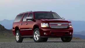 A burgendy 2011 Chevrolet Suburban LTZ full-size SUV parked on gravel in front of misty mountains