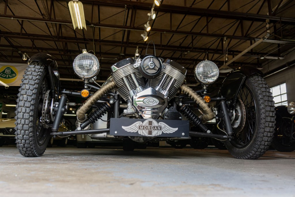 The front view of a 2012 Morgan 3-Wheeler in a car-filled garage
