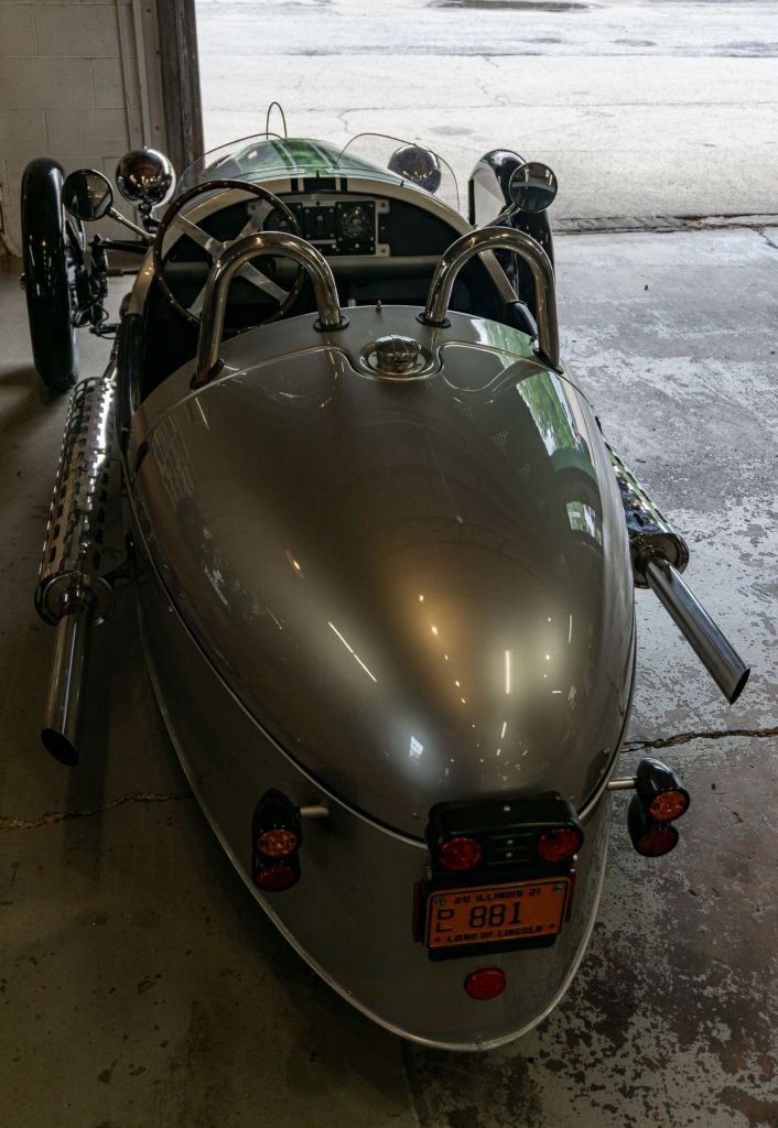 An overhead rear view of a silver 2012 Morgan 3-Wheeler in a garage
