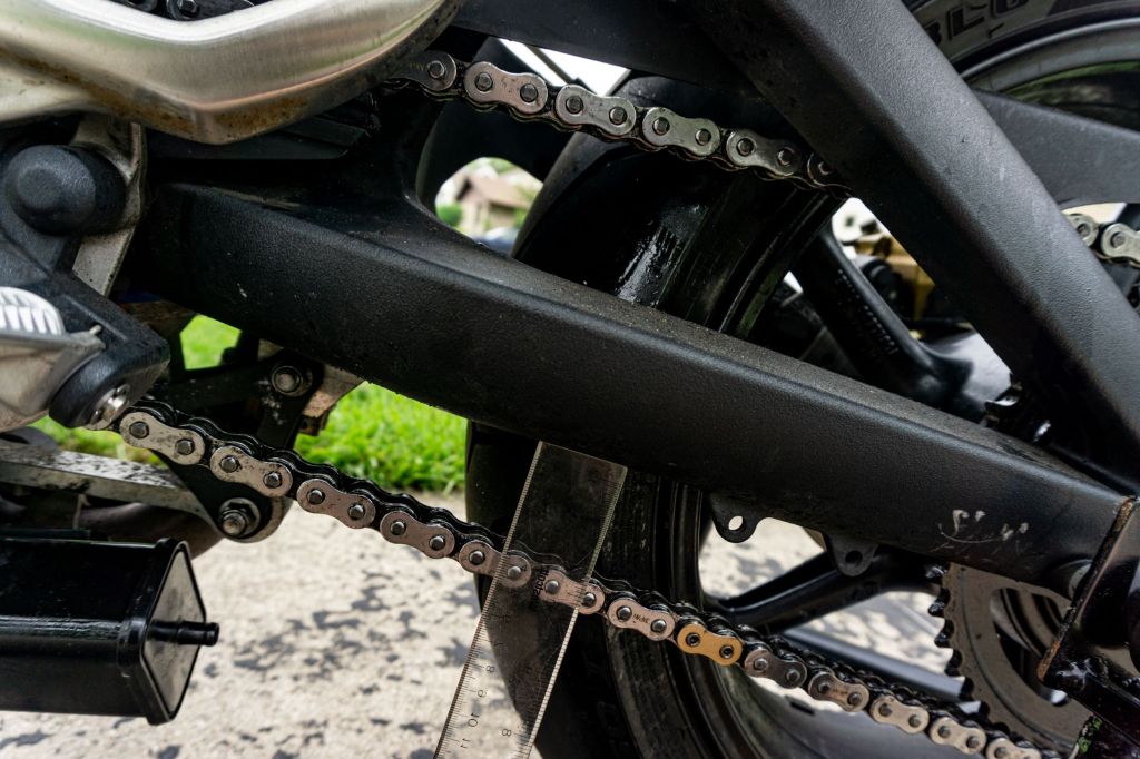 Checking the chain slack on a 2012 Triumph Street Triple R motorcycle with a ruler