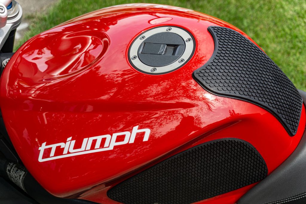 An overhead left-side view of a red 2012 Triumph Street Triple R with black tank grips installed
