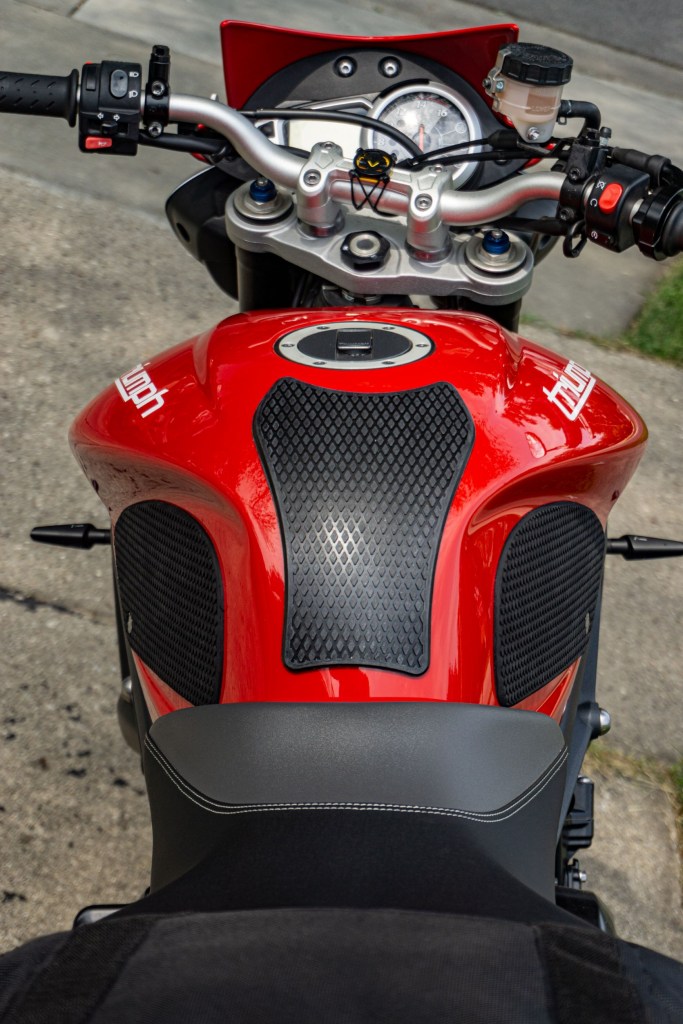 The rider's view of a red 2012 Triumph Street Triple R with black tank grips installed