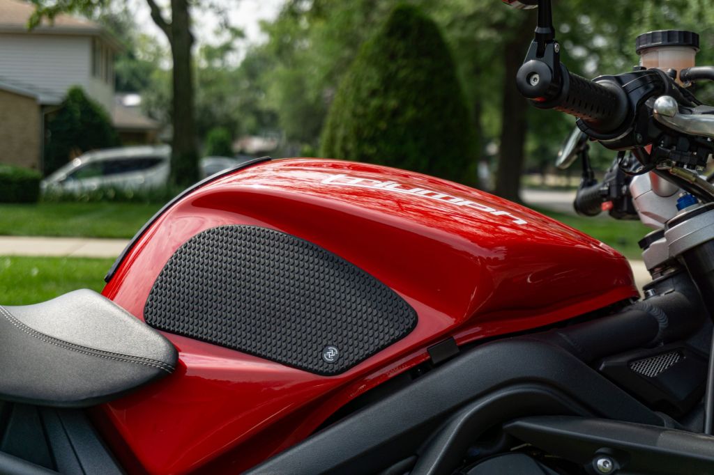 The right side of a red 2012 Triumph Street Triple R with black tank grips installed