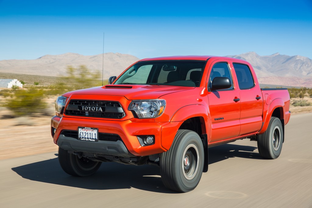 a bright red 2015 Toyota Tacoma TRD Pro off-road pickup truck driving on a sandy trail