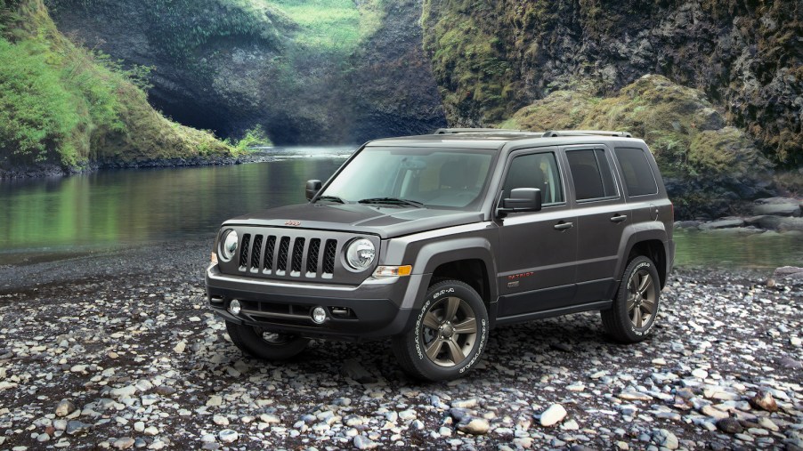A grey 2016 Jeep Patriot parked along a river bed, the 2016 Patriot is one of the worst used cars you can buy
