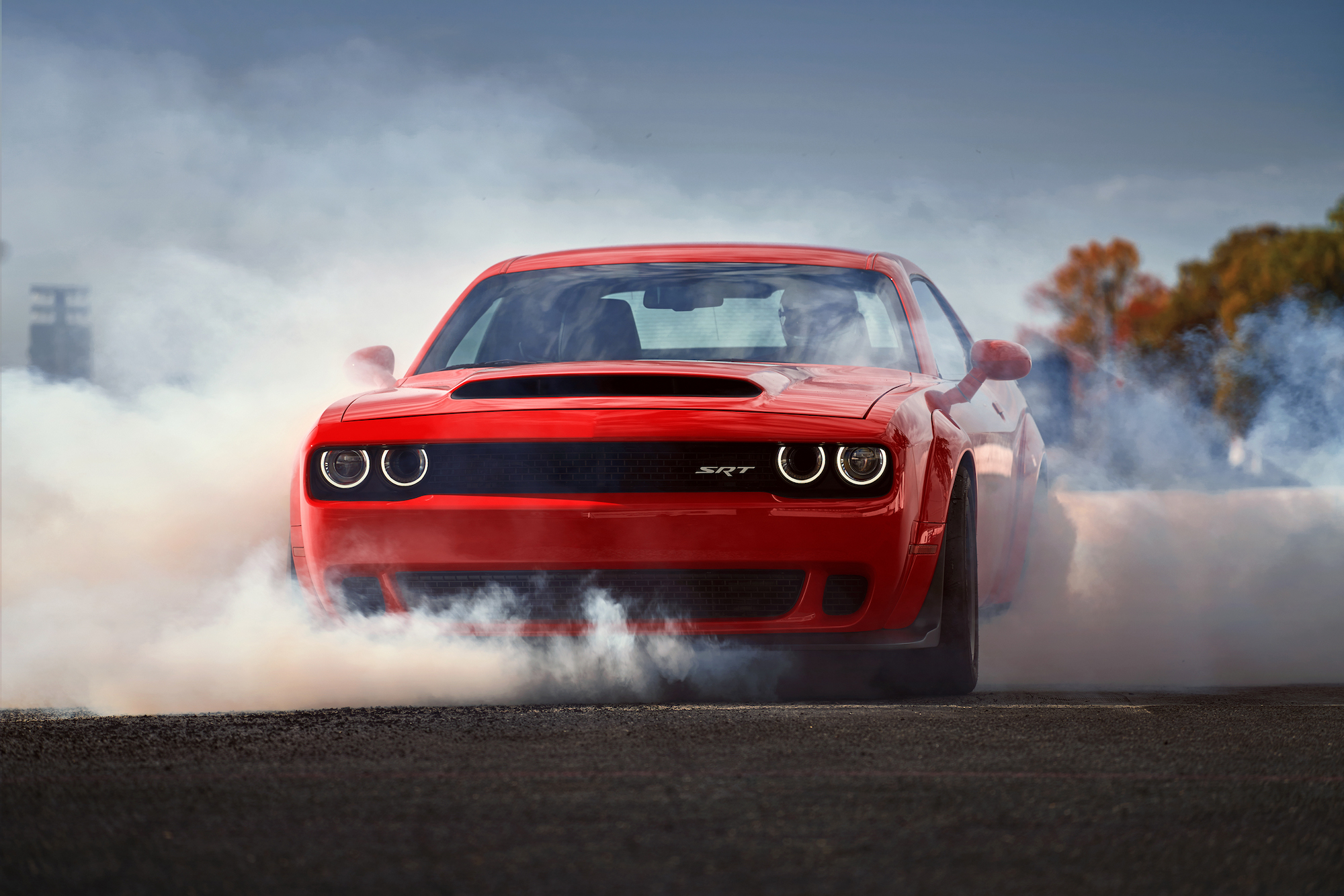 A red 2018 Dodge Challenger SRT Demon doing a burnout. The Demon is among the top fastest muscle cars of all time.