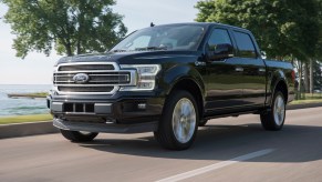 A 2019 Ford F-150 driving on a tree lined street, the 2019 Ford F-150 is the best used full-size truck under $25K and outranks the Chevy Silverado and the Ram 1500