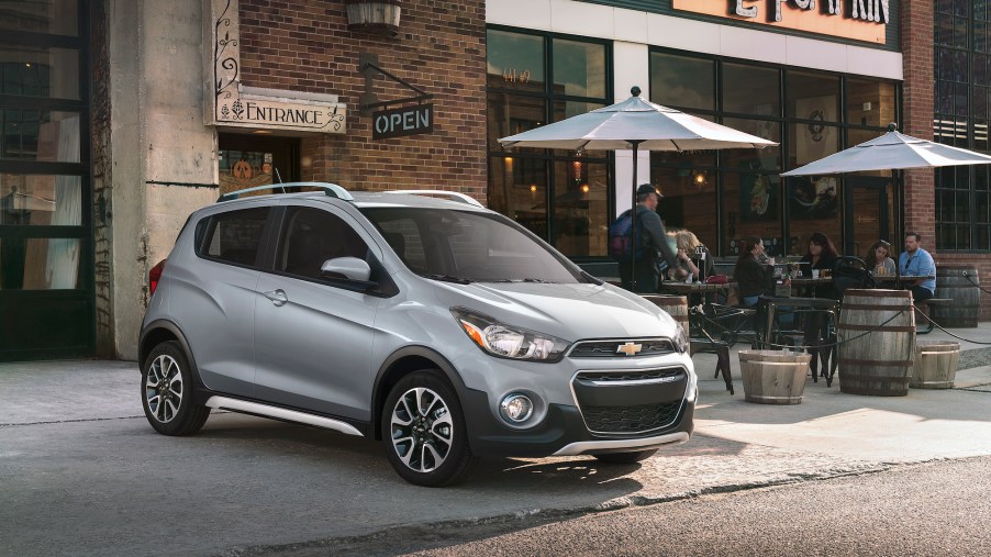 A silver 2021 Chevy Spark three-door hatchback parked outside a Jolly Pumpkin bakery and café