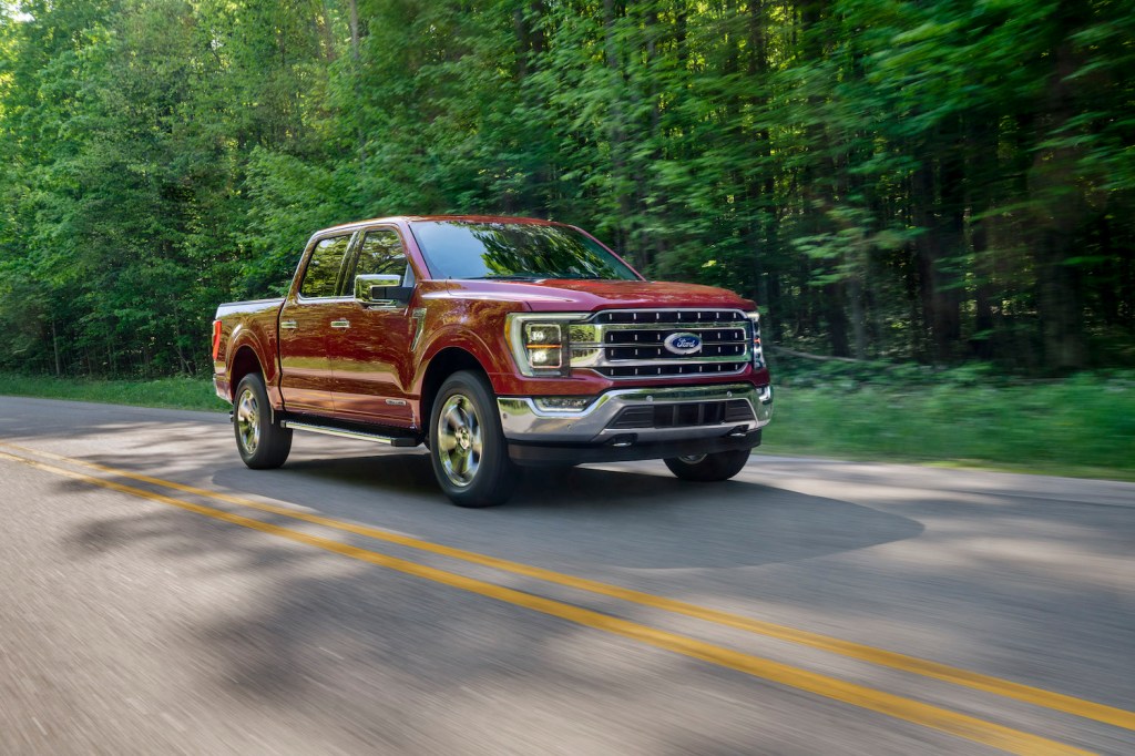 A red 2021 Ford F-150 driving, the latest Ford F-150 recall includes the truck's seatbelts
