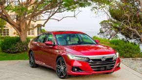 The 2021 Honda Accord Hybrid sedan in red parked outside of a luxury home near cobblestone