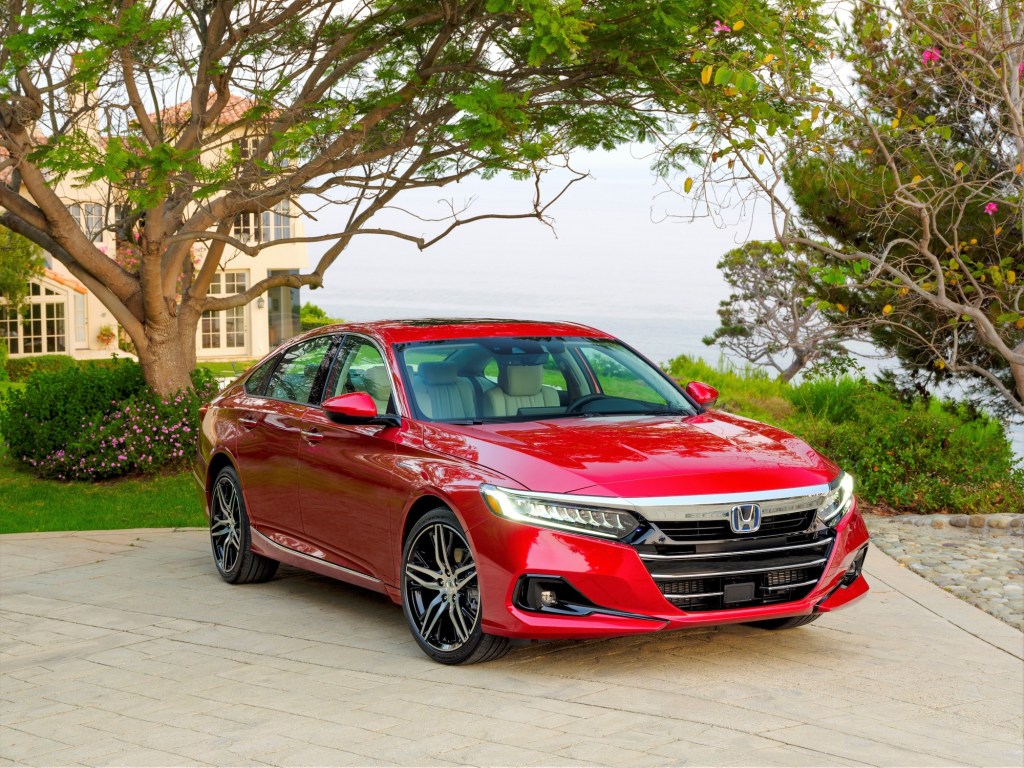 A red 2021 Honda Accord Hybrid parked in a driveway outside Mediterranean-style home