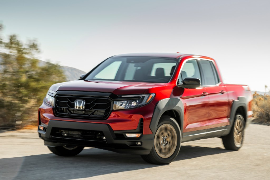 A red 2021 Ridgeline Sport with HPD Package driving on a sunny day, the Ridgeline is the best midsize truck of 2021
