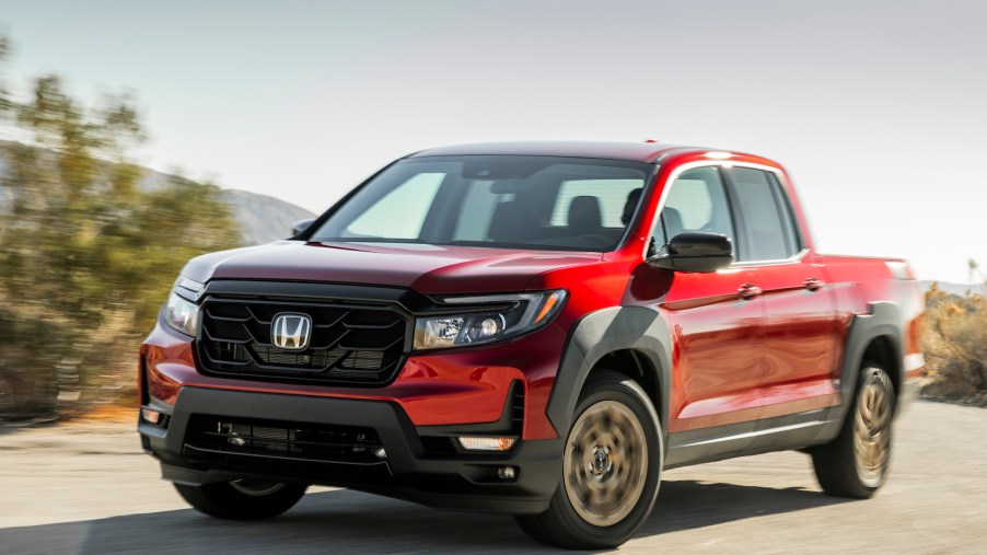 A red 2021 Ridgeline Sport with HPD Package driving on a sunny day, the Ridgeline is the best midsize truck of 2021
