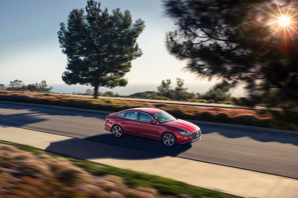A red 2021 Hyundai Sonata driving by trees, the 2021 Hyundai Sonata is one of the least reliable Hyundai models