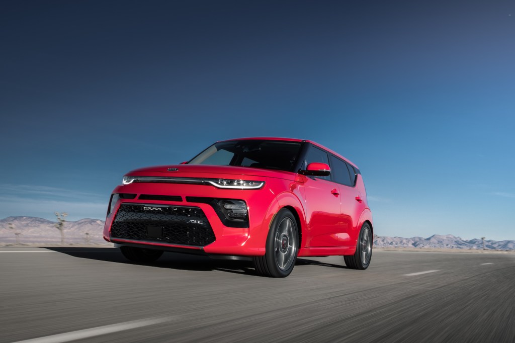 A red 2021 Kia Soul driving along an empty road, the 2021 Kia Soul is one of the best first new cars 