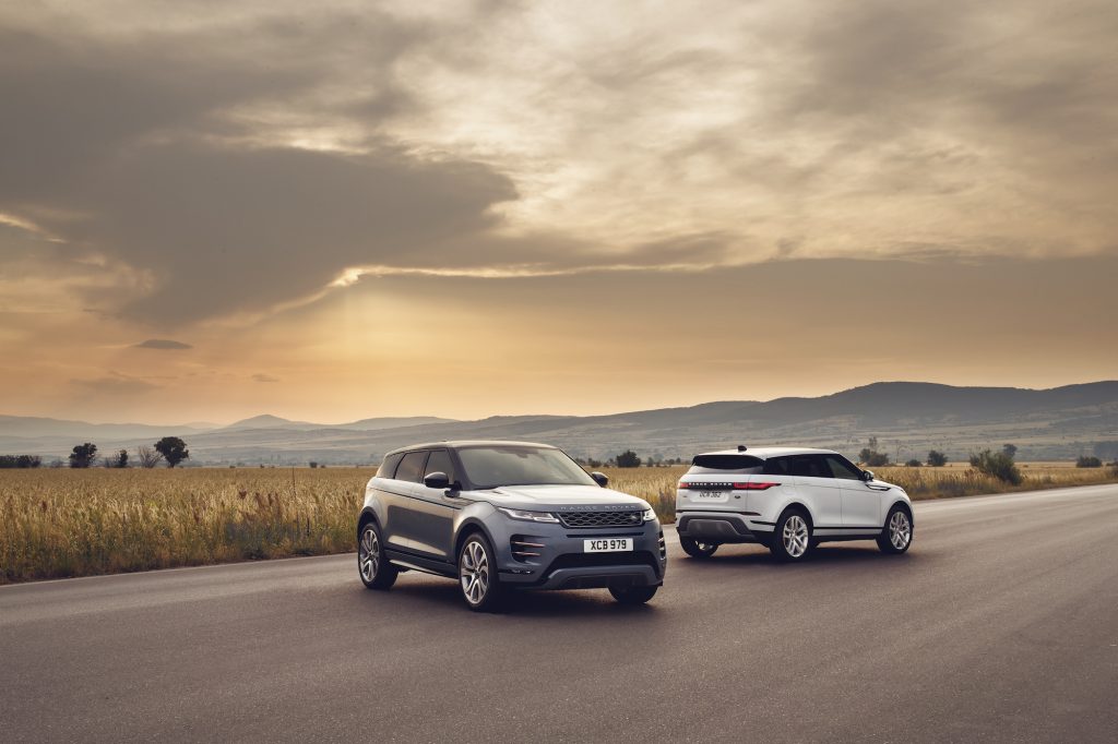 Two 2021 Land Rover Range Rover Evoque luxury compact SUVs parked on a road through a plain in front of mountains