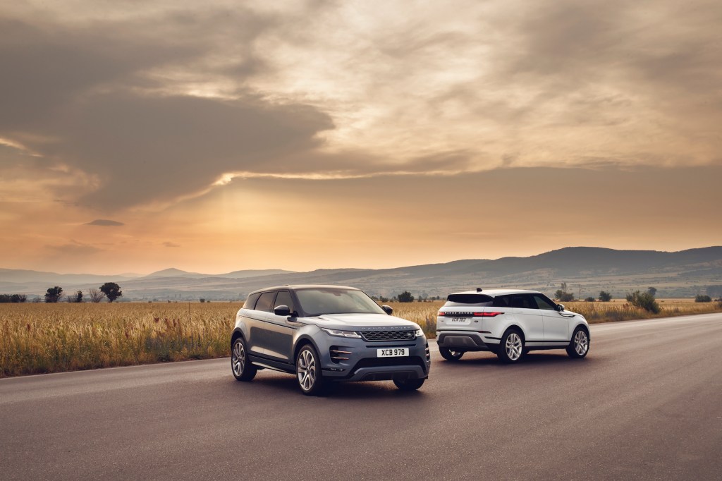 Two 2021 Land Rover Range Rover Evoque luxury compact SUVs parked on a road through a plain in front of mountains