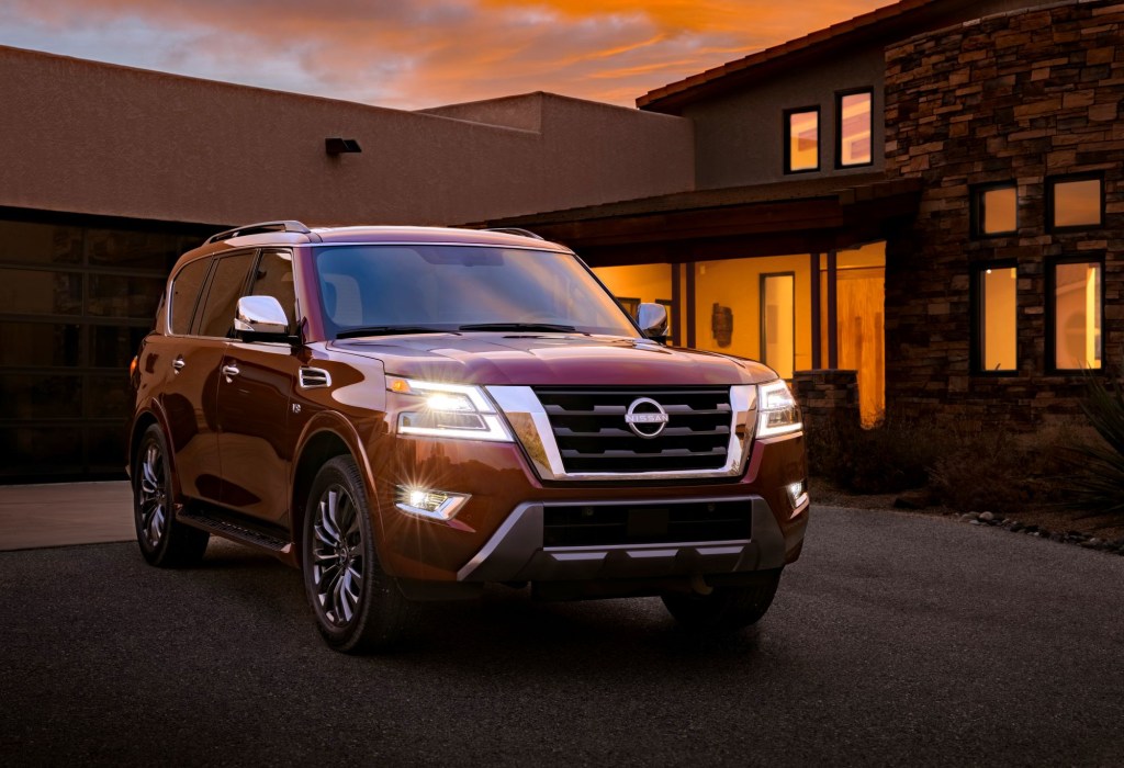 The 2021 Nissan Armada full-size SUV model in red parked outside of a house at sunset