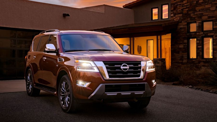 The 2022 Nissan Armada full-size SUV model in red parked outside of a house at sunset