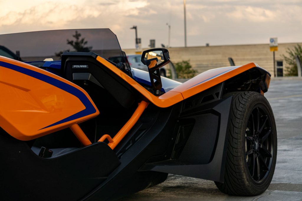 A closeup of an orange-and-blue 2021 Polaris Slingshot R's passenger's side