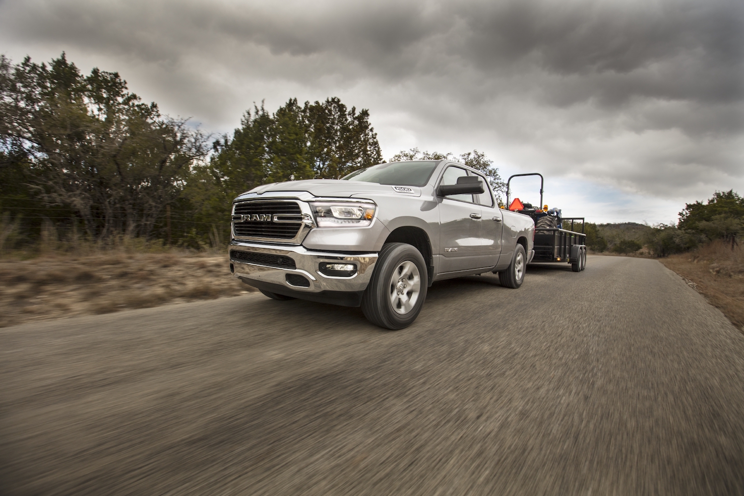 A silver 2021 Ram 1500 towing a heavy load