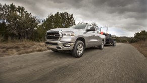 A silver 2021 Ram 1500 towing a heavy load