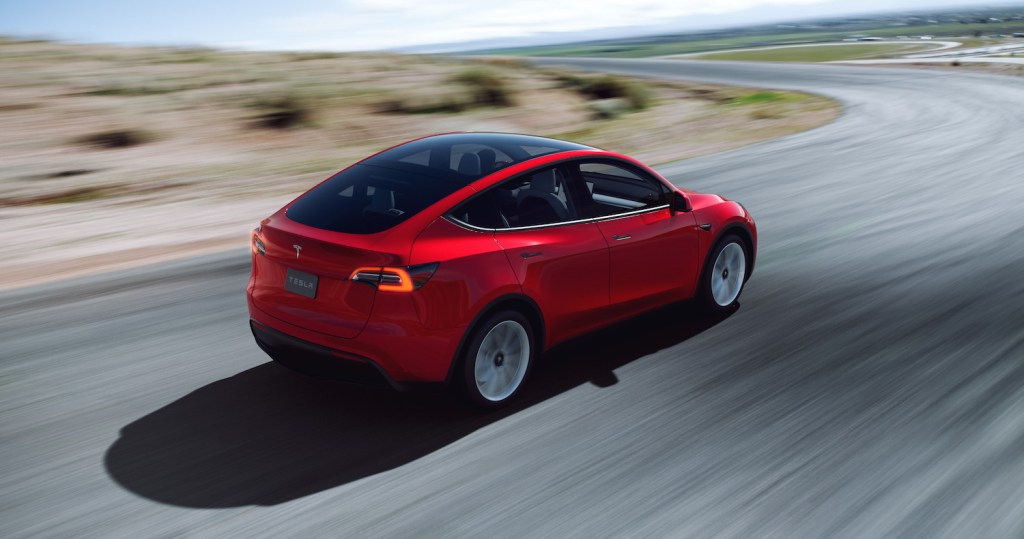 A red 2021 Tesla Model Y driving around a bend
